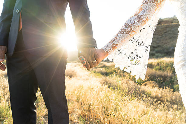 A bride and groom holding hands in the desert